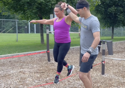 Deux participants d’un atelier de team building FlipToP à Québec pratiquent l’équilibre sur slackline en plein air.